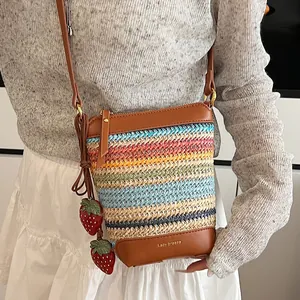 Rainbow striped straw crossbody bag with brown leather trim and cute strawberry charms