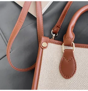 Detailaufnahme der Canvas-Tasche mit braunen Ledergriffen und goldenen Metallteilen