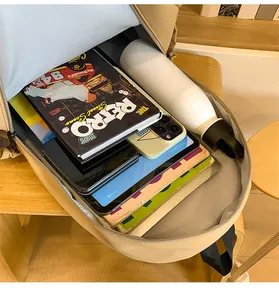Macro detail of spacious backpack interior holding a tablet, books, and water bottle