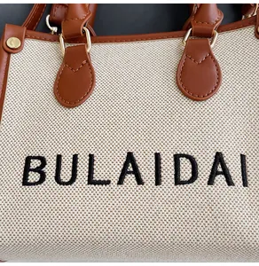 Detailaufnahme der Leinwandstruktur und der braunen Lederpaspel an der Stickerei-Tasche