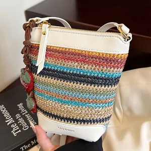 Colorful woven straw bucket bag with white leather straps and strawberry charms