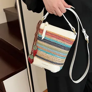 Rainbow woven straw crossbody bag with white leather trim and strawberry charm detail