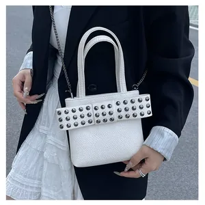 Détail d'un sac en cuir blanc avec un grand nœud clouté et une bandoulière chic