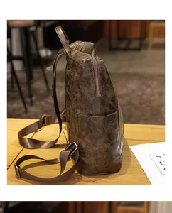 Λεπτομέρεια vintage καφέ δερμάτινου σακιδίου με πλαϊνή τσέπη και ρυθμιζόμενο λουράκι
