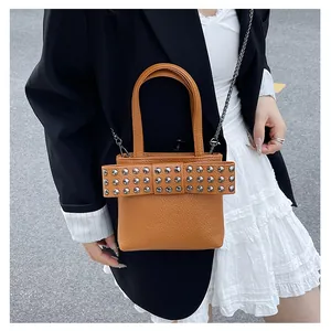 Détail du sac à main en cuir marron avec nœud à rivets et bandoulière en chaîne métal