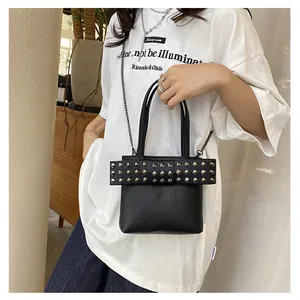 Détail du sac à main en cuir grainé avec rivets argentés et bandoulière en chaîne