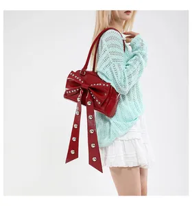 Detailed macro view of large red bow with silver rivets on shiny patent leather handbag