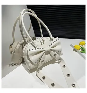 Detail view of cream shoulder bag with large bow decoration and silver metal rivets