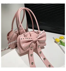 Detail of light pink patent leather handbag with bow decoration and silver metal studs