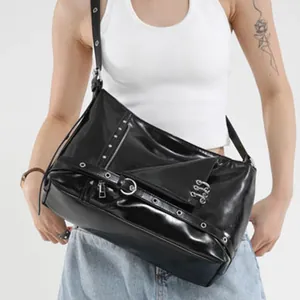 Sac cabas noir brillant style punk avec rivets métalliques et boucles porté par un mannequin