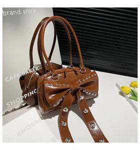 Detail of coffee brown bow handbag featuring silver rivets and glossy leather finish