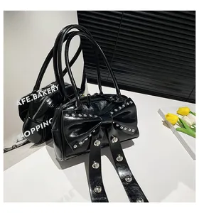 Detailed view of black patent leather bag with large bow and silver metal rivets