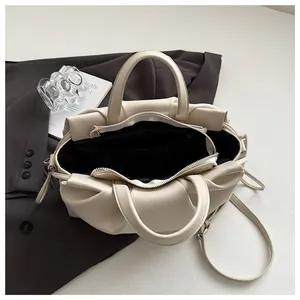 Detail view of cream pleated cloud bag showing black lining and interior zipper pocket
