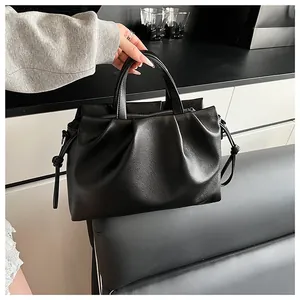 Detailed close-up of ruched black leather bag with soft texture and sturdy handles
