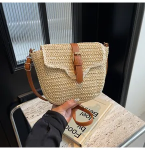Detail van handgeweven strooien crossbodytas met bruine lederen riem en een metalen gesp sluiting