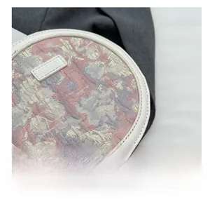 Vue détaillée du tissu jacquard floral rose et des coutures blanches sur le sac rond