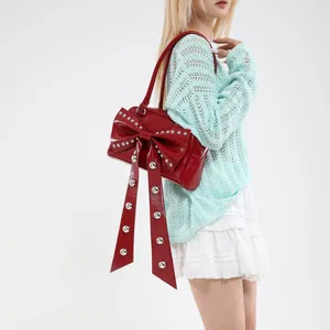 Chic red bow shoulder bag with silver studs and glossy finish on model