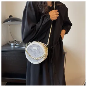 Détail du sac bandoulière rond blanc avec motif floral et chaîne de perles