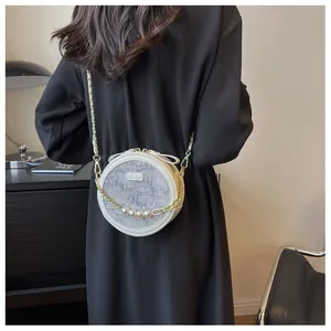 Détail du sac à bandoulière rond blanc avec perles décoratives et un élégant nœud