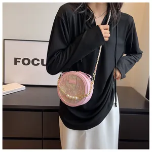 Détail du sac bandoulière rond rose avec texture en tweed et chaîne dorée à perles