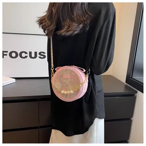 Détail du petit sac rond rose avec jacquard floral et chaîne décorative en perles