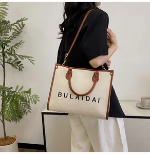 Detailansicht der bestickten Canvas-Tasche mit braunen Ledergriffen und Tragegurt