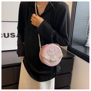 Gros plan du sac rond rose clair avec chaîne de perles et détails en tissu tissé