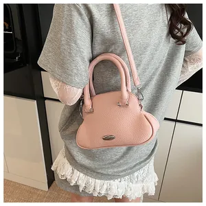 Detail of pink lychee grain leather handbag showing texture and metallic buckle ornament