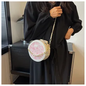 Détail du sac à bandoulière rond crème avec motif rose et décoration en perles
