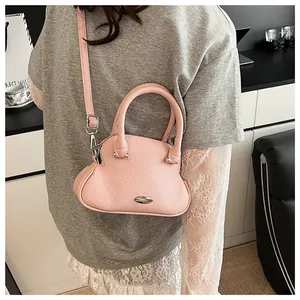 Close-up of pink lychee leather handbag with metallic detail and cylindrical top handle