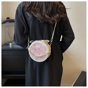 Détail du sac bandoulière rond à fleurs avec cuir blanc, nœud et chaîne de perles dorées