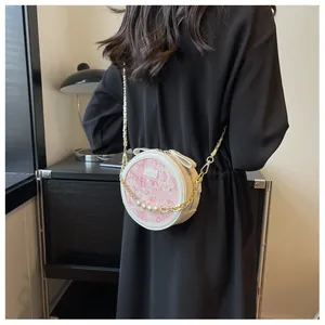 Détail du sac bandoulière rond avec chaîne dorée à perles et imprimé floral rose