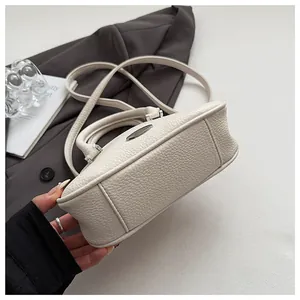 Detail of off-white lychee texture faux leather bag with silver hardware and neat stitching