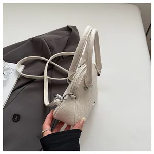 Close-up of cream white lychee texture leather handbag with triangular metal ornament
