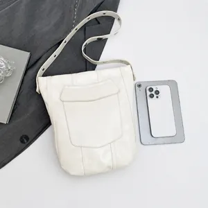 Détail du sac seau en cuir ivoire avec bandoulière réglable et poche avant pratique