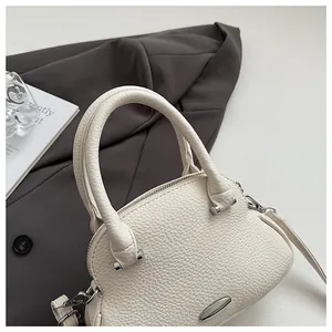 Close-up of off-white lychee grain leather texture and metallic hardware on a handbag