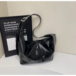 Detail of glossy black leather tote with silver buckle and vertical zipper design