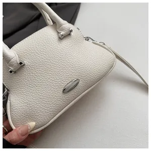 Detail of premium cream white leather handbag featuring silver hardware and lychee texture