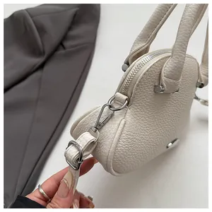 Detail of off-white lychee pattern leather handbag with silver zipper and metal buckle