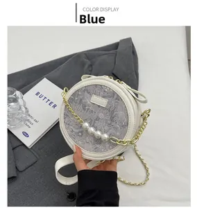 Détail du sac rond blanc avec garniture en dentelle grise et bandoulière perle