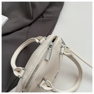 Detail view of cream lychee texture leather handbag with silver metallic zipper