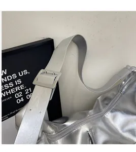 Detail of silver metallic tote bag featuring wide adjustable shoulder strap and metal buckle