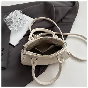 Overhead detail of cream pebbled leather handbag interior with zipper pocket and silver hardware
