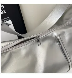 Detailed macro view of the smooth metal zipper on this silver metallic tote bag