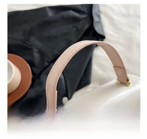 Detail shot of the elegant pink handbag featuring a smooth leather handle and silver logo