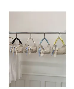 Dettaglio di borse tessute con finiture in pizzo e ciondoli decorativi con perle