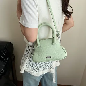 Pale green pebble leather crossbody bag with cloud shape shown on model