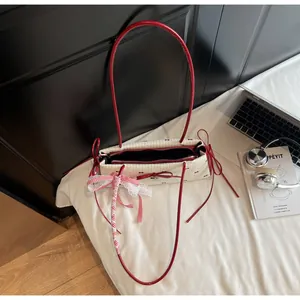 Detail of white canvas shoulder bag with red ribbon bows and lace pendant accessory