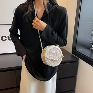 Sac rond rose texturé avec bandoulière en chaîne dorée et pendentif en perles