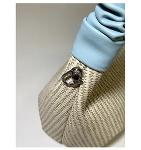 Dettaglio della borsa in paglia intrecciata con finiture in pelle azzurra e anello di metallo